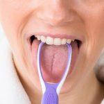 Woman using a tongue scraper
